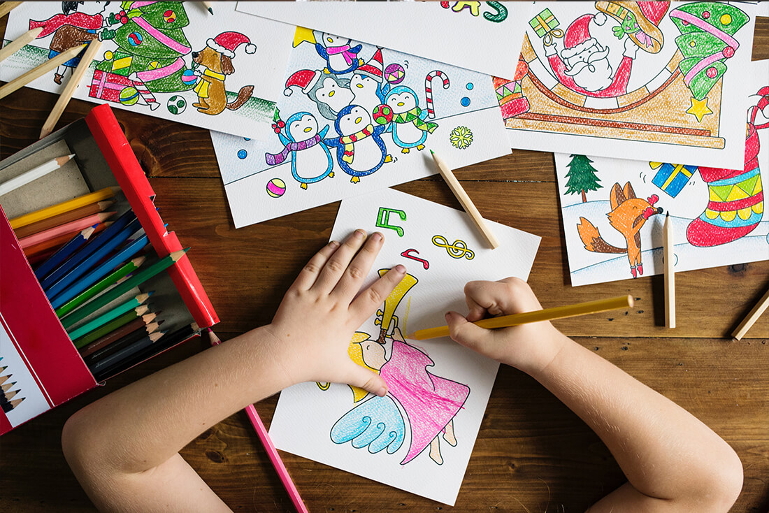 Child colouring in pictures on different pieces of paper.